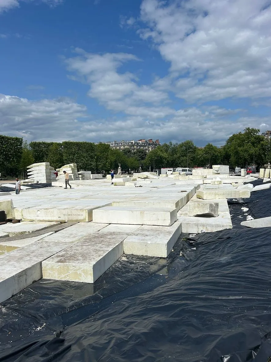 Une fois le polystyrène positionné, une bâche est posée et des panneaux de répartition de 350kg chacun sont placés, pour solidifier et tasser le tout et de mieux répartir la charge du sable de la piste. 